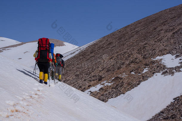 一群背包客带着徒步旅行的电线杆穿过白雪覆盖的斜坡