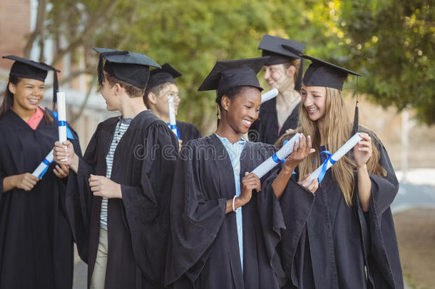 研究生学校的孩子们站在校园里拿着学位卷轴