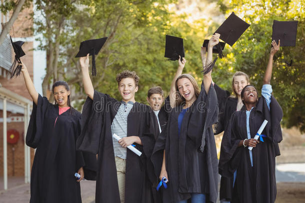 研究生学校的孩子们站在校园里，拿着学位卷轴和黑板