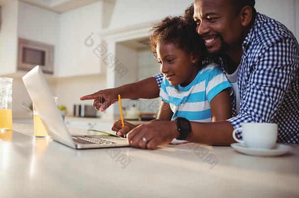 父亲在帮助女儿做家庭作业时使用笔记本电脑