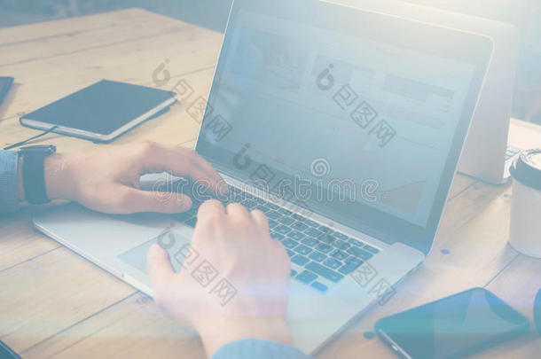 商人在木桌上用笔记本电脑工作。男人在笔记本键盘上发短信。水平，视觉效果。