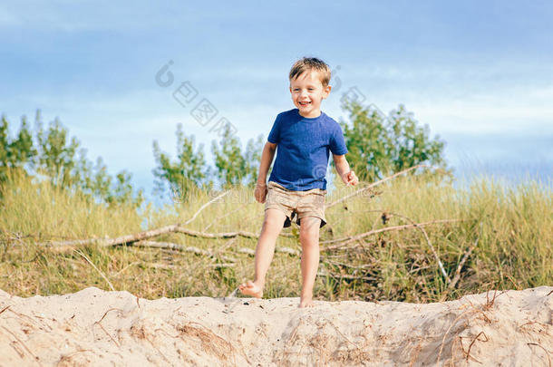 高加索儿童男孩在沙丘海滩上玩耍，在阳光明媚的夏日靠近森林