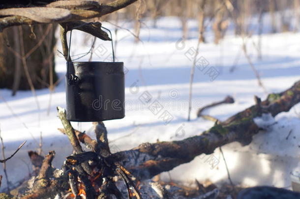 在冬天的森林里，火上的一壶沸水温暖着，