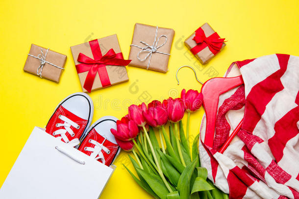 一束红色郁金香，红色胶鞋，凉爽的购物袋，衣架上的条纹夹克和美妙的黄色礼物