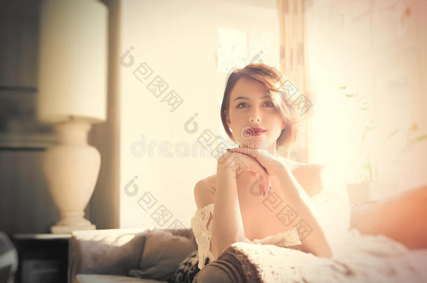 美丽的年轻女人坐在沙发上，在轻奢的房间里微笑