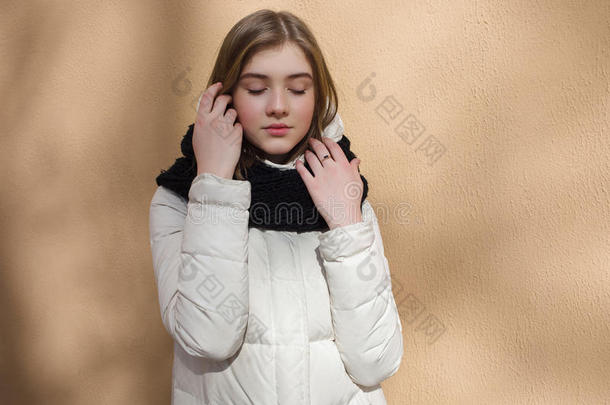 寒冷的季节，年轻美丽的女人闭着眼睛，穿着白色的外套，摆出<strong>质感</strong>的墙壁，<strong>带</strong>有光影图案的生活方式自负