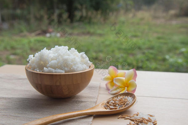 在木碗和勺子里煮米饭，在木头背景上煮米饭。