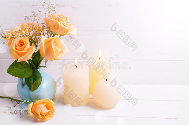 在蓝色花瓶里燃烧蜡烛和桃色玫瑰花