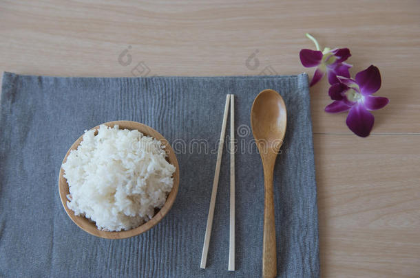 把米饭放在木碗和勺子里，筷子放在木头背景上。