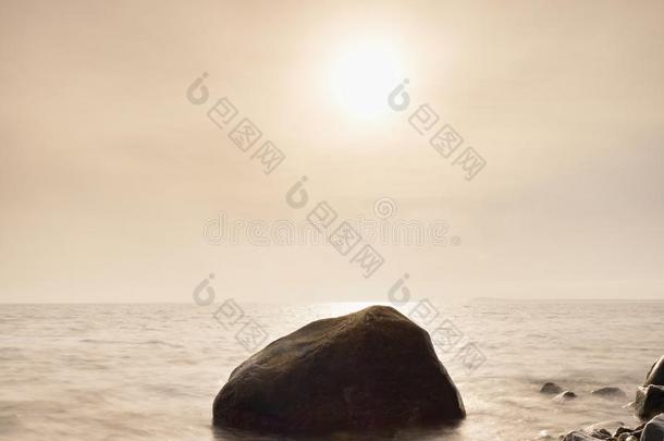 岛岸的巨石从光滑的大海上伸出。 石质海岸抵御海浪