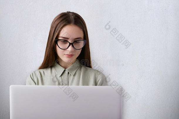 教育和工作理念。 一个可爱的女孩，有着<strong>长长</strong>的黑发和迷人的脸，在她的工作场所用电脑看