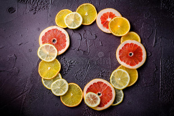 柠檬、橘子、葡萄柚的柑橘类水果片在深色背景上呈圆形。