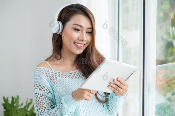 享受窗台风景和听音乐的亚洲女人。