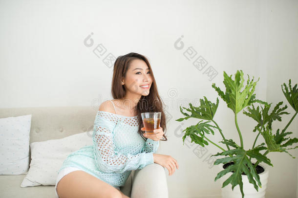 美丽的年轻亚洲妇女在家里早餐时喝着早茶。
