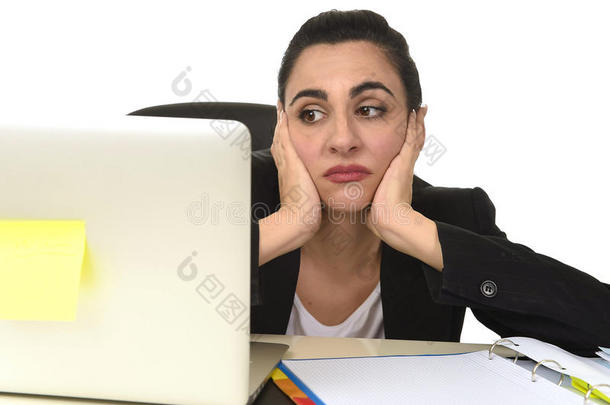 穿着西装的有魅力的女人在办公室的电脑桌上工作很累很无聊，看上去很难过
