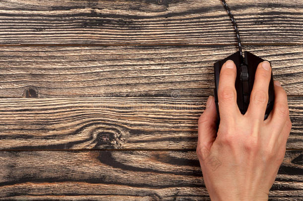 黑色计算机鼠标与一只手在黑色木制背景与复制空间为您的文本。 上面的风景