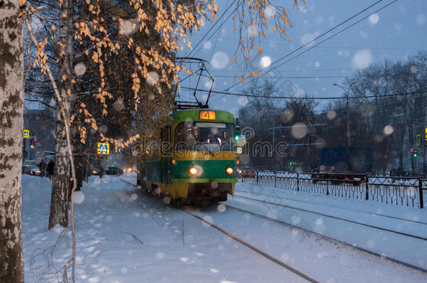 绿黄色的电车在黄昏下雪时绕城而行。