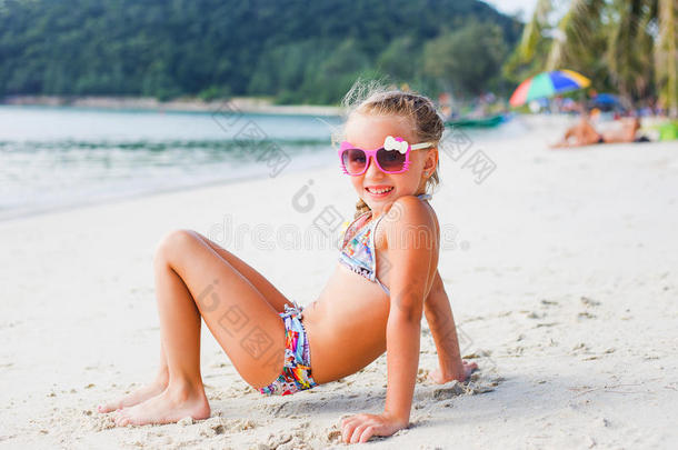 可爱的小女孩戴着太阳镜和泳衣在海边的天堂海滩上。 旅行和度假。 自由概念。 泰国