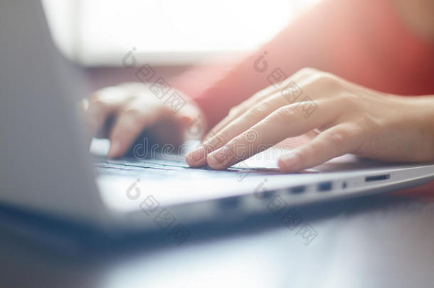 妇女的特写肖像`她的手在坐在桌子旁的笔记本电脑上打字。 女商人通过笔记本电脑在线工作