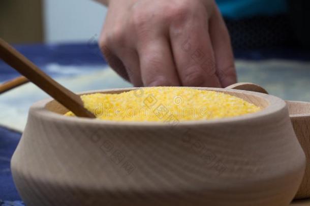 玉米面粉放在木碗里，勺子放在家里的桌子上。