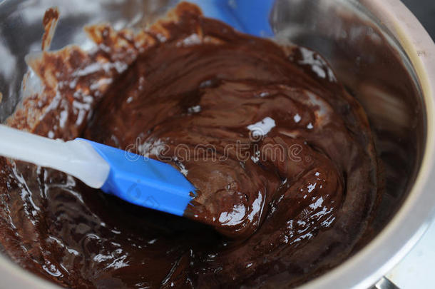 巧克力和黄油在水浴中融化。蓝色硅胶抹刀。制作甜点或甜点的过程