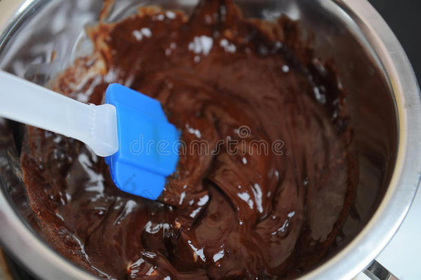 <strong>巧克力</strong>和黄油在水浴中融化。蓝色硅胶抹刀。制作甜点或甜点的过程