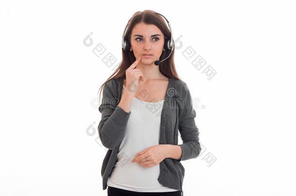 穿着t恤和灰色夹克的忧郁的年轻女孩看着远方，听着耳机