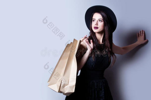 美丽的年轻女人，购物袋站在美妙的白色工作室背景前