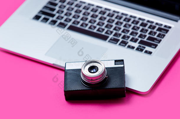 美丽的黑色相机和凉爽的笔记本电脑在美妙的粉红色背景