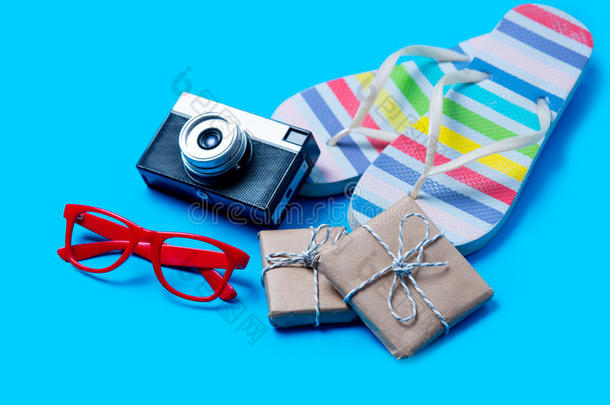 五颜六色的凉鞋，眼镜，相机和可爱的礼物在美妙的蓝色背景