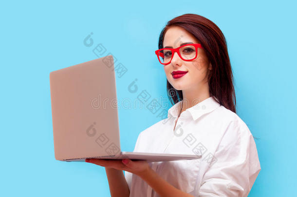 美丽的年轻女人，笔记本电脑站在美妙的蓝色背景前