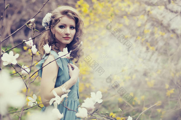 美丽的金发女郎，美丽的发型，穿着老式的蓝色连衣裙，穿着郁郁<strong>葱葱</strong>的春天花园玉<strong>兰</strong>