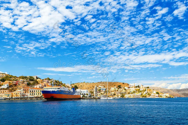 希腊多德卡尼索斯的客海渡船在西米岛海湾的山丘和蓝色背景下定期进行海上交通