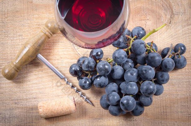 一杯红酒，木桌上有一串葡萄。