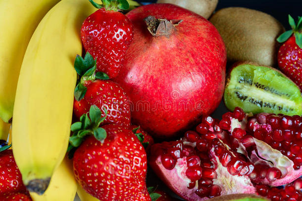 介绍新鲜天然水果、有机草莓、半石榴石、香蕉和猕猴桃、黑色背景、健康食品，