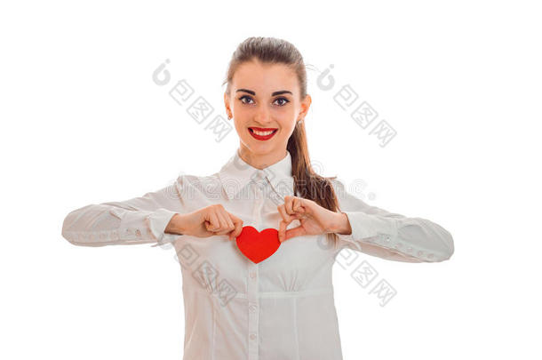 美丽的年轻女孩vbeloj衬衫和红色口红在嘴唇上，拿着一张心形的卡片，微笑着
