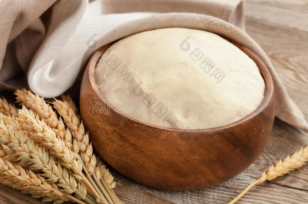 面团放在木碗里，成熟的小麦耳朵放在旧木板上。 农村概念。