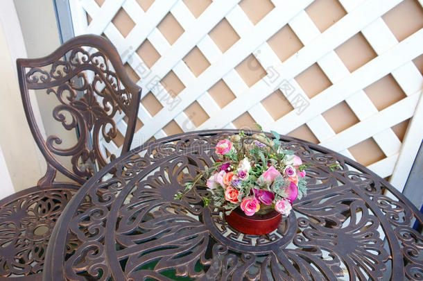 用粉红色玫瑰花瓶雕刻的桌子和椅子。 白色木制背景，复古风格。