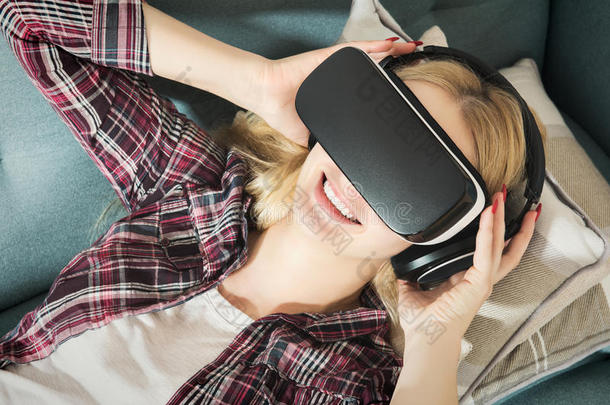 躺在沙发上戴着虚拟现实眼镜的漂亮女人。虚拟现实耳机。生活方式虚拟现实