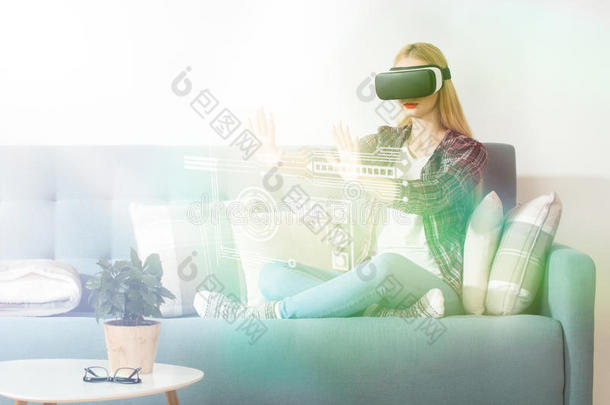 迷人的女人戴着虚拟现实眼镜坐在沙发上。 虚拟现实耳机。 生活方式虚拟现实