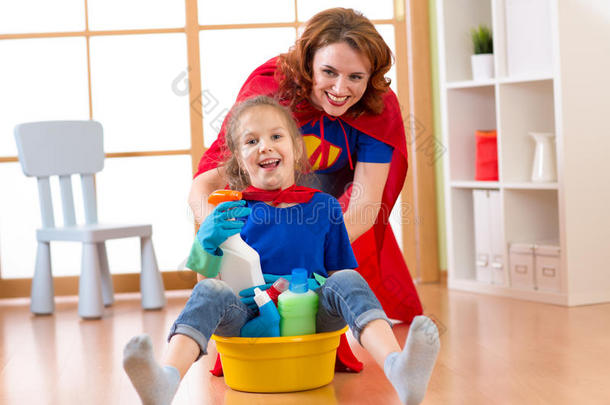 美丽的母亲和她可爱的小女儿穿着超级英雄的清洁和玩耍