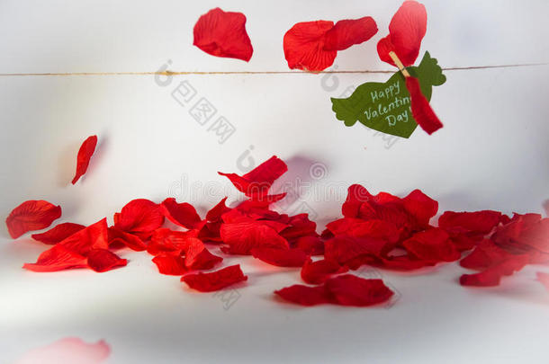 绿色的纸心，翅膀和祝贺，用衣针固定在一根绳子上，红色的花瓣飘落。