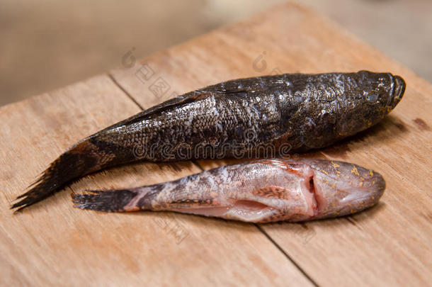 新鲜死鱼在木制砧板上烹饪食物。