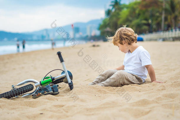 活跃的金发男孩和自行车在海边。 蹒跚学步的孩子在温暖的夏天做梦和玩得开心。 户外游戏给孩子