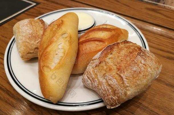 各种不同类型的法国面包作为配菜与咸黄油在桌子上，焦点在前地面面包与模糊