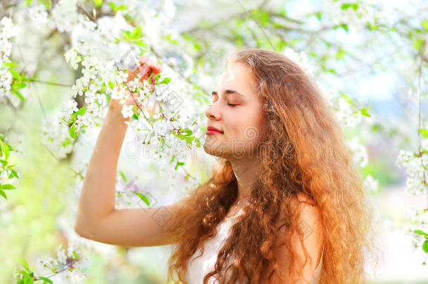 美丽的年轻女人喜欢闻春天的花在花园里