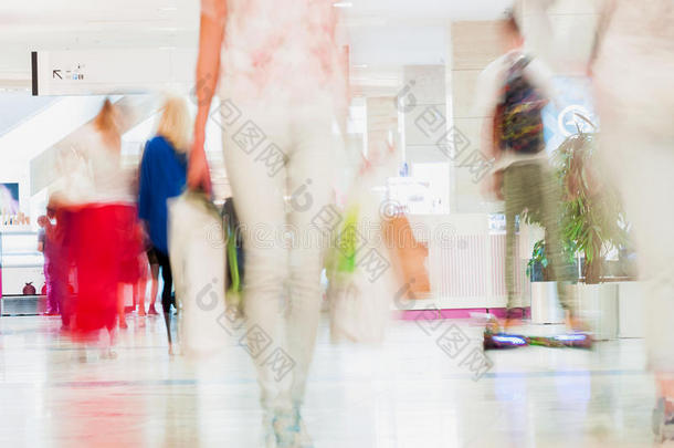 抽象的离焦运动模糊了年轻人在购物中心散步。 一个购物的女孩的美丽形象