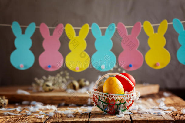 复活节组成复活节彩色鸡蛋在篮子和兔子花环在木制背景。