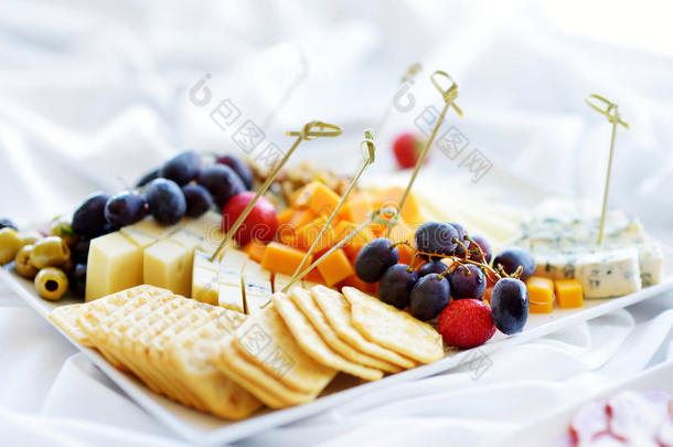 不同种类的葡萄酒小吃：白色桌子上的奶酪、饼干、水果和橄榄