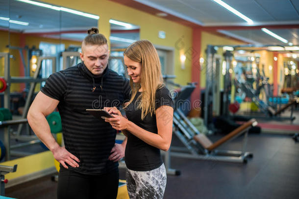 适合有吸引力的年轻夫妇在健身房看平板电脑，<strong>因为</strong>他们监测他们的进步和健身